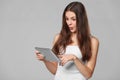 Happy girl in white shirt using tablet. Excited woman with tablet pc, isolated on grey background Royalty Free Stock Photo