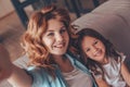 Happy girl and woman taking selfie on smartphone sitting on the couch