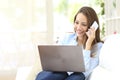 Happy girl working with laptop calling on phone at home