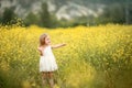 Happy girl in a yellow dress staying in the field of flowering rape. Nature blooms rape seed field