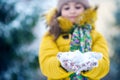 Happy girl in yellow jacket plays with snow. Children games in winter