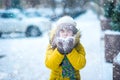 Happy girl in yellow jacket plays with snow. Children games in winter..