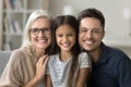 Happy girl, young dad and grandmother sitting close on sofa Royalty Free Stock Photo