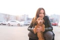 Happy girl and young dog posing against the background of a city landscape at sunset. Portrait of dog owner and puppies