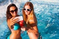 Happy girlfriend with a drink on a summer party by the pool take