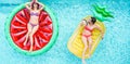 Happy girls floating with tropical fruit lilos inside swimming pool - Young women friends relaxing in summer vacation at resort Royalty Free Stock Photo