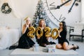 Happy girls friends holding 2020 golden balloons at New Year party, having fun together. New Year Eve 2020 party