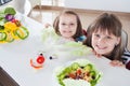 Happy girls making funny salad faces. Cooking vegetarian meal Royalty Free Stock Photo