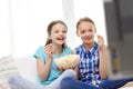 Happy girls with popcorn watching tv at home Royalty Free Stock Photo