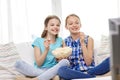 Happy girls with popcorn watching tv at home Royalty Free Stock Photo