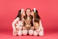 Happy girls in pyjamas kissing elder sister sitting together with teddy bears, sisterly love.