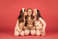 Happy girls in pyjamas kissing elder sister sitting together with teddy bears, sisterly love.