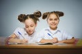 Happy girls sitting at desk on gray background. school concept Royalty Free Stock Photo