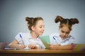 Happy girls sitting at desk on gray background. school concept Royalty Free Stock Photo