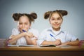 Happy girls sitting at desk on gray background. school concept Royalty Free Stock Photo