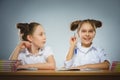 Happy girls sitting at desk on gray background. school concept Royalty Free Stock Photo