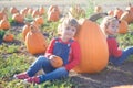 Happy girls sitting near huge pumpkin at farm field patch Royalty Free Stock Photo