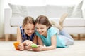 Happy girls with smartphones lying on floor