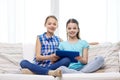 Happy girls with tablet pc sitting on sofa at home Royalty Free Stock Photo