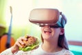 Happy girls in virtual reality glasses eating sandwich