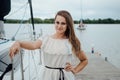 Happy glamorous beautiful girl in a white light dress on a background of a lake. Sexy girl on the background of the promenade of