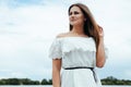 Happy glamorous beautiful girl in a white light dress on a background of a sky Royalty Free Stock Photo