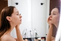 Happy glamour girl looking in mirror, applying mascara on eye lashes in bathroom. Young woman putting on cosmetic product for Royalty Free Stock Photo