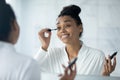 Happy glamour millennial girl looking in mirror, applying mascara Royalty Free Stock Photo