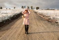 Happy go lucky woman walking down dirt road in light snow fall