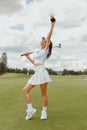 Happy golf champion woman holds the winner& x27;s golden cup over her head.