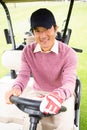 Happy golfer driving his golf buggy