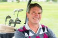 Happy golfer driving his golf buggy smiling at camera Royalty Free Stock Photo