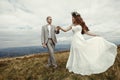 Happy gorgeous bride and groom holding hands and dancing in sun Royalty Free Stock Photo