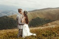 happy gorgeous bride and groom hugging in sun light, boho wedding couple, luxury ceremony at mountains with amazing view, space f