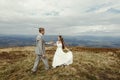 Happy gorgeous bride and groom walking in sun light, boho weddi Royalty Free Stock Photo