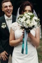 Happy gorgeous bride hiding at bouquet and stylish groom laughing and having fun. emotional moment of beautiful wedding couple Royalty Free Stock Photo