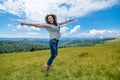 Happy gorgeous girl enjoy mountain view jumping on the hill with breathtaking mountain landscape