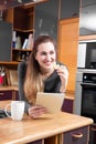 Happy gorgeous girl relaxing in holding a tablet in kitchen
