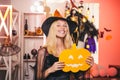 Happy gothic young woman in witch halloween costume with hat standing and smiling over white background. Vampire