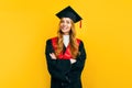 Happy graduate in a master`s dress, on a yellow background. Concept of the graduation ceremony Royalty Free Stock Photo