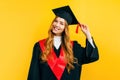 Happy graduate in a master`s dress, on a yellow background. Concept of the graduation ceremony Royalty Free Stock Photo