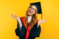 Happy graduate in a master`s dress, on a yellow background. Concept of the graduation ceremony Royalty Free Stock Photo