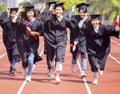 Happy graduation students  holding diploma and running on the stadium at school Royalty Free Stock Photo