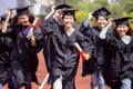 Happy graduation students  holding diploma and running on the stadium at school Royalty Free Stock Photo