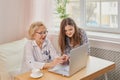 Adult granddaughter teaching her elderly grandmother to use laptop Royalty Free Stock Photo