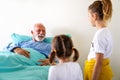 Happy grandchildren visiting grandfather at hospital ward. Support, family and healthcare concept. Royalty Free Stock Photo