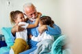 Happy grandchildren visiting grandfather at hospital ward. Support, family and healthcare concept. Royalty Free Stock Photo