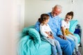 Happy grandchildren visiting grandfather at hospital ward. Support, family and healthcare concept. Royalty Free Stock Photo