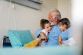 Happy grandchildren visiting grandfather at hospital ward. Support, family and healthcare concept. Royalty Free Stock Photo