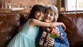 Happy granddaughter girl hugging grandma on sofa at home Royalty Free Stock Photo